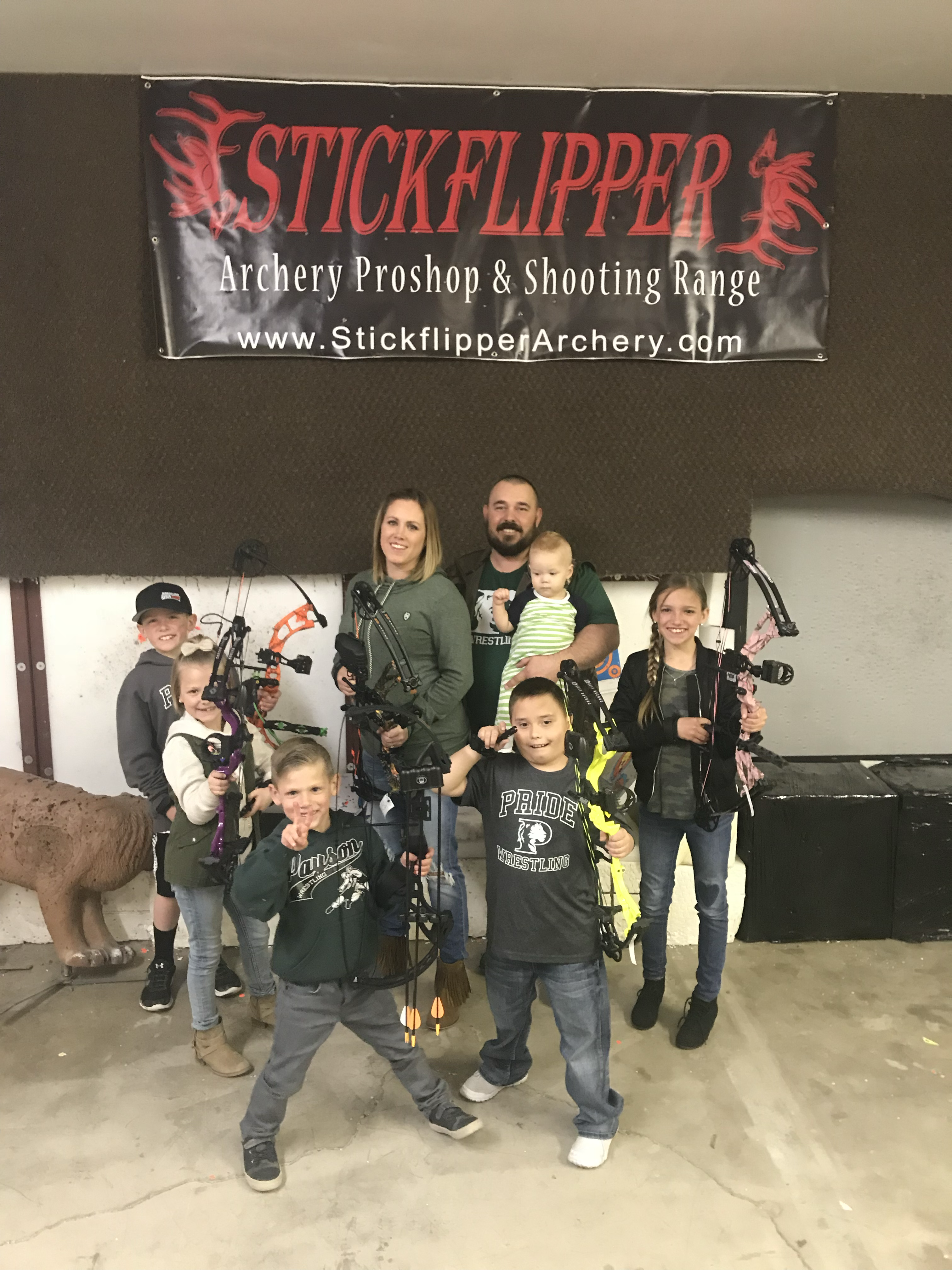 The Stickflipper family with their bows under the shop banner